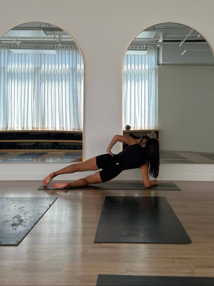 Side-lying oblique lift and lower, hand on hip, in a bright studio